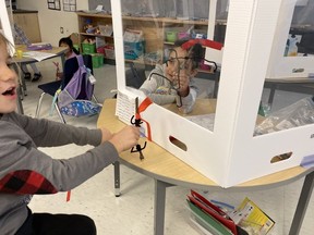 Students at Kanata Highlands Public School work at their desks separated by plastic shields.