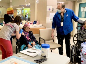 RPN team lead Andrea McWatters, left, administers the first Moderna COVID-19 vaccine to Eunice Fiddler as her daugter Margaret Beardy (centre) and interpreter Tom Chapman look on at the Sioux Lookout Meno Ya Win Health Centre on Thursday, Jan. 7.