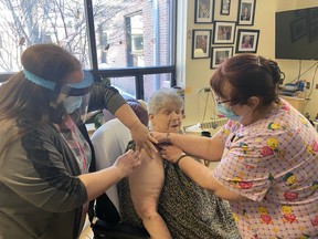 Heather Lucier, RPN, (left) assisted by Virginia Lemay, RN, (right) gives the first COVID-19 vaccination to Sharron Kropp at Pinecrest Home for the Aged in Kenora on Wednesday, Jan. 27. The Northwestern Health Unit received 300 doses of the Moderna COVID-19 vaccine and has begun rolling them out to long-term care residents in the region.