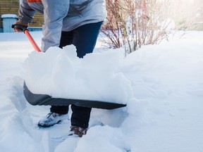 Man clearing snow by shovel after snowfall. Outdoors.