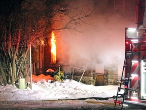 Flames shoot from a ground-floor window as a firefighter shuts off gas to a building on McIntyre Street East, Saturday morning.
PJ Wilson/The Nugget