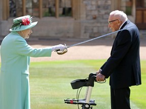 Queen Elizabeth II awards Capt. Sir Thomas Moore with the insignia of Knight Bachelor July 17 at Windsor Castle. The Second World War British Army veteran raised almost $45 million for National Health Service charities by walking 100, 25-metre laps of his garden using a walker, at 10 laps a day. Chris Jackson/Getty Images