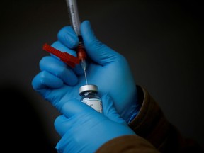 A health-care worker draws a dose of the Moderna COVID-19 vaccine from a vial.