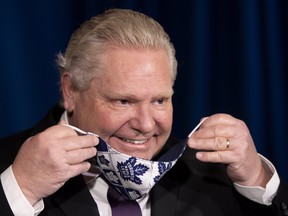 Ontario Premier Doug Ford puts on his Toronto Maple Leafs mask during the daily briefing in Toronto on Monday, February 8, 2021.  THE CANADIAN PRESS/Frank Gunn ORG XMIT: fng104