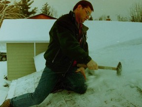 Russell Colborne chops away at ice on his roof, on Jan. 29, 1998.