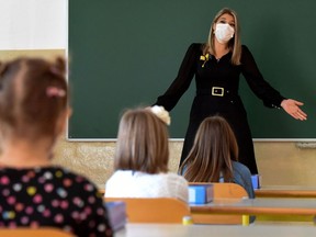 A teacher wearing a protective mask to prevent the spread of the novel coronavirus gives a course in a classroom.
