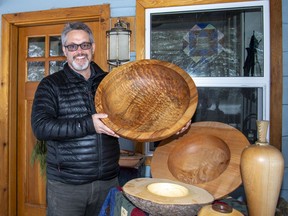 Woodturner Bill Hunt holds a massive 23 inch diameter wooden bowl made from a spectacular piece of Big Leaf Maple salvaged from Canada's west coast. Some of his other work is displayed on the table at his home in Harvie Heights. photo by Pam Doyle/www.pamdoylephoto.com