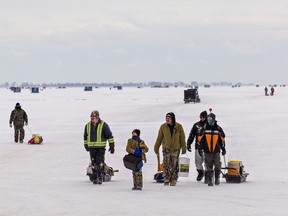 People walk back to shore pulling their gear after spending the morning ice fishing on frozen Lake Erie at St. Williams, Ontario on Friday.