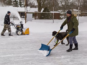 Jay Lesky (left) and Jeff Vandermey clear snow from the neighbourhood skating rink at Grand Woodlands Park.