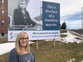 Tammy Skillings, a registered practical nurse at St. Joseph's Lifecare Centre, stands in front of a billboard at the long-term care facility that features her photograph. The billboard is part of a campaign to recognize front-line workers.