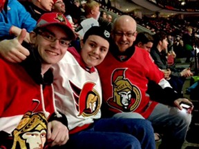 Brian Fraser, left, who turned his fight with leukemia into a much-publicized awareness campaign, died Thursday night at age 26. He is pictured here at an Ottawa Senators game with his brother, Tait, and father Rick. (SUBMITTED PHOTO)