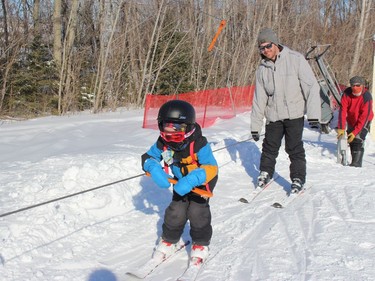 Jacob Rose makes his way up the hill, with dad Martin Rose not far behind, and Big Ben volunteer Ron Lauzon at the tow lift controls. Photo on Sunday, February 21, 2021, in Cornwall, Ont. Todd Hambleton/Cornwall Standard-Freeholder/Postmedia Network