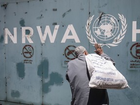 A photo taken on July 31, 2018, shows a Palestinian man standing in front of the emblem of the UN Relief and Works Agency for Palestine Refugees in the Near East outside the agency's offices in Gaza City. Russia backed a Palestinian proposal for a Middle East peace conference, suggesting on Jan. 27, 2021, it could be held at ministerial level in spring or summer, as the U.S. said it would move towards renewing ties with the Palestinians under new U.S. President Joe Biden.