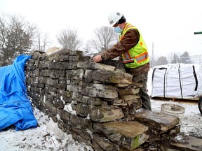 Stonemason consultant John Scott looks over a dry stone wall that is being dismantled on the property of the Kingston Frontenac Public Library's Pittsburgh Branch to make way for the widening of Gore Road. The wall will be rebuilt once the road work is done.