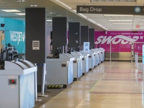 Empty lines of check-in desks for Air Canada, WestJet and Swoop at London International Airport. (Mike Hensen/The London Free Press)