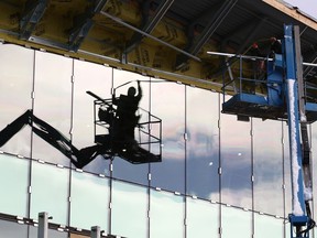 A worker is reflected in windows as he works on the Place des Arts facility in downtown Sudbury on Feb. 8, 2021.