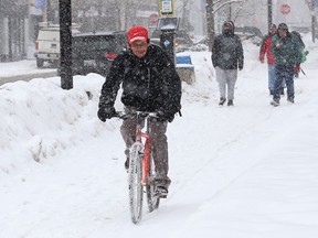 A cyclist and pedestrians navigate a snow-covered sidewalk on Durham Street in Sudbury, Ont. on Wednesday February 24, 2021.