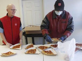 Timmins' Salvation Army supervisor Craig Wilson, left, and Paul Bedard, one of the volunteers, were preparing meals on Wednesday as they are currently offering only take-out meals. On Wednesday, they were handing out pizza slices, soup and sandwiches for people experiencing homelessness in town. 

RICHA BHOSALE/The Daily Press