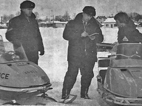 It takes one to catch one  – Cochrane OPP detachment members have two snowmachines at their disposal. Constable Gary Stevens (right) gives a fake ticket to a young snowmobiler. Both he and Cpl. Jack Korry agree that the vehicles are invaluable in patrolling and ticketing erring snowmobilers. Failing to stop, driving without a license and racing are among the common offences.