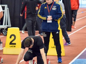 Joseph Burke watches while a Laurentian athlete gets set up in the blocks at an indoor track meet.