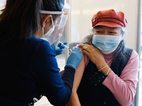 Margaret Nicholson receives her first dose of the Pfizer COVID-19 vaccine from a nurse at the Wabano Centre for Aboriginal Health on Feb. 18. New recommendations suggest it's possible to delay the second shot for up to four months.