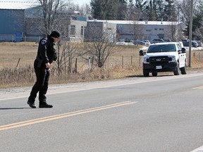 Const. Zane Brillinger scans Days Road for any pieces of evidence on Friday, after a woman was struck and killed in the area by a vehicle in a hit and run the evening before.