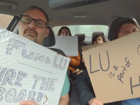 A family concerned about the future of Laurentian University holds up the signs they created for a recent car rally.