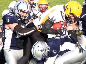 Sudbury Spartans Ben DeBenedet (27) and Riley Roy (17) tackle North Bayy Bulldogs ball-carrier Jesse Pledge during Northern Football Conference action at James Jerome Sports Complex in Sudbury, Ontario on Saturday, june 1, 2019.