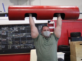 Leif Palsen does an overhead log lift at Crude Strength and Performance in downtown Fort McMurray on Sunday, March 28, 2021. At the time of this photo, Alberta's COVID-19 rules had rules on capacity, masks, and how low-intensity and high-intensity exercises can be performed. Vincent McDermott/Fort McMurray Today/Postmedia Network