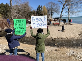 Normandale residents brought signs of protest to the beach Saturday as politicians answered questions from a crowd of about 100 people about how the small public beach property came to be offered for sale.