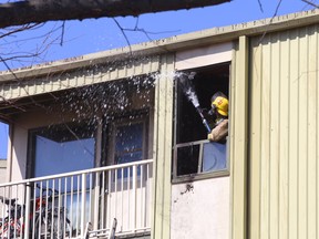 A Kingston Fire and Rescue firefighter blasts water inside a third-floor apartment at 780 Division St. in Kingston on Monday.