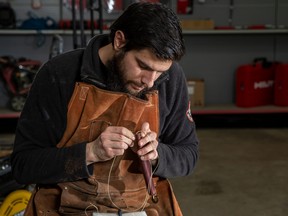 Blacksmith and knife maker Alessio Zilli of AZ Custom Knives Ltd. works on a sheath for some hunting knives he has made.   RANDY VANDERVEEN