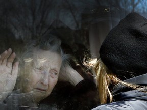 Diane Colangelo visits her 86-year-old mother Patricia through a window at the Orchard Villa long-term care home in Pickering.