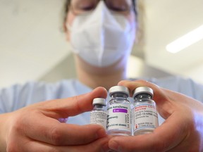 A worker holds vials of Pfizer-BioNTech, AstraZeneca and Moderna vaccines for COVID-19.