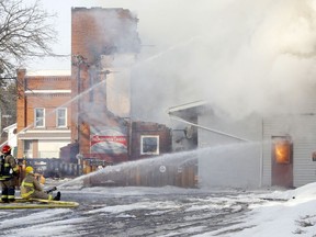 Firefighters spray water on the burning remnants of the Tweedsmuir Tavern Wednesday in Tweed. Walls not destroyed by fire were later demolished using heavy equipment.