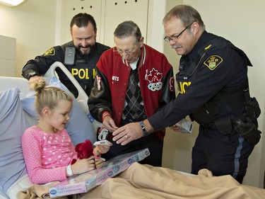 Walter Gretzky joins Ontario Provincial Police Cst. Jim Gallant (left) of Brant OPP and Cst. Jim Wallace of the London Highway Safety Division visiting eight year old Jillian deBlieck, a patient at Brantford General Hospital on Tuesday December 20, 2016 in Brantford, Ontario. The officers are members of the Golden Helmets precision motorcycle team, who have been visiting area hospitals to spread Christmas cheer to patients. Brian Thompson/Brantford Expositor/Postmedia Network