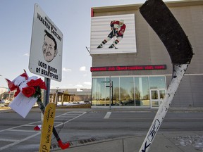 Hockey sticks and floral tributes are placed Friday at Walter Gretzky's reserved parking spot at the Wayne Gretzky Sports Centre in Brantford.