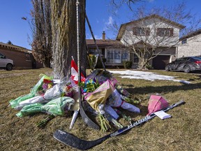 Hockey sticks and floral tributes are placed on the front lawn of Walter Gretzky's home in Brantford.