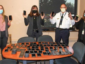 Ontario Provincial Police West Region Headquarters staff (from left) Ashley Anderson, Staff Sgt.Victoria Loucks, Chief Superintendent Dwight Thib - OPP WR Commander,
and Dawn Orr show some of the 200 surplus cell phones that are being donated to eleven victims services agencies in Ontario. OPP PHOTO