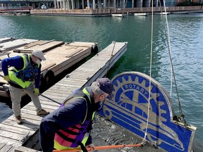 Rotarians Ed Coon, left, and Ray Marshall clean the silt off the Old Meg sculpture as a crane lifts it from Tunnel Bay on Tuesday afternoon. (RONALD ZAJAC/The Recorder and Times)