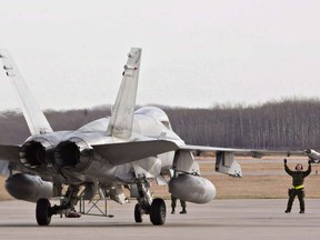 Military personnel guide a CF-18 Hornet into position at the CFB Cold Lake, in Cold Lake, Alberta on Tuesday October 21, 2014. THE CANADIAN PRESS/Jason Franson