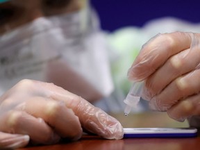 A medical worker works on a sample after testing a patient for COVID-19.