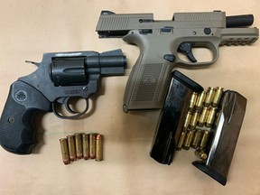 Two loaded handguns were seized and two people face dozens of charges after a traffic stop on Highway 401 in Loyalist Township on Sunday.
