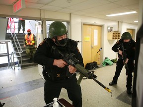 Military police officers storm a building on Canadian Forces Base Kingston during a training exercise on Wednesday. The exercise simulated the response to a shooting at the building by a pair of armed attackers.