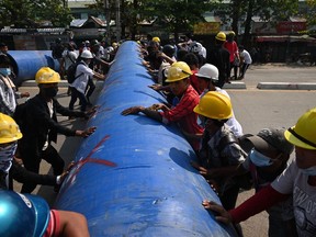 Protesters roll a large pipe to build a barricade as they take part in a demonstration against the military coup in Yangon, Myanmar, on March 11.