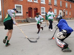 Queen’s University housemates Griffin MacNaughton, from left, James Griffin, Oliver Narowski-Vesely and Ross Cameron, background, takes shots on goaltender James Lank. All live on Earl Street across from the Athletics and Recreation Centre and celebrated St. Patrick’s Day with a road hockey game and a party (just for them) on their front lawn on Wednesday.
