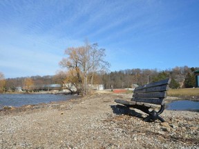 A bench sits along the  waterfront trail on Owen Sound's shoreline. High water and waves in recent years have heavily damaged the trail, and covered it with rocks and debris.