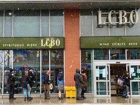 Customers line up to enter a LCBO store in Ottawa Monday during the COVID-19 outbreak. Beer, wine and liquor stores can remain open.