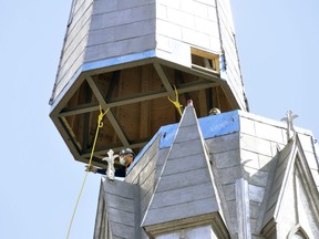 On-site workers guide a 40-foot piece, complete with a seven-foot cross, on the steeple of St. Patrick's Church in Kinkora March 24. It's been 17 1/2 years since the steeple has been in place, a landmark for miles around that parishioners say makes the Catholic church complete once again. (ANDY BADER, Postmedia Network)