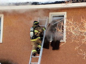 Firefighter Ian Caughey of the Pembroke Fire Department breaks a second-storey window to vent the smoke Tuesday afternoon after fire broke out at a Metcalfe Street home at the corner of Cecelia Street. Nobody was home at the time, but some animals succumed to their injuries. The cause of the fire is under investigation.
